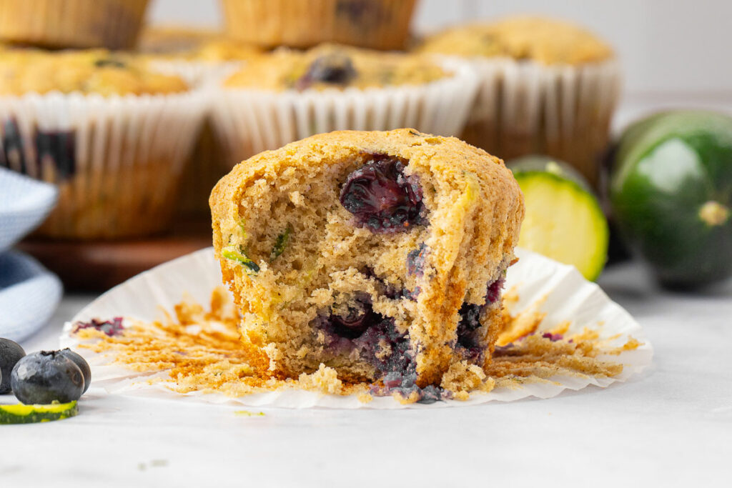 Zuchhini blueberry muffin sitting on a plate with a bite taken out of it.