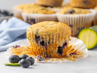 Zucchini blueberry muffin sitting on an opened muffin liner.