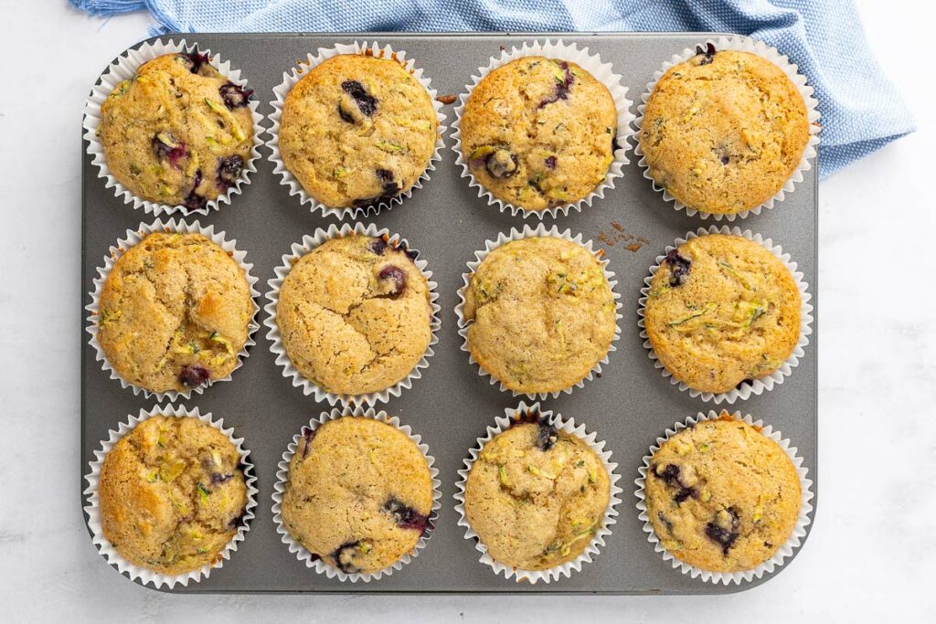 Baked zucchini blueberry muffins fresh out of the oven and still in the muffin tin.