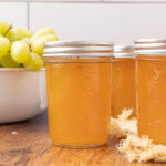 Jars of grape jelly sitting on a countertop.