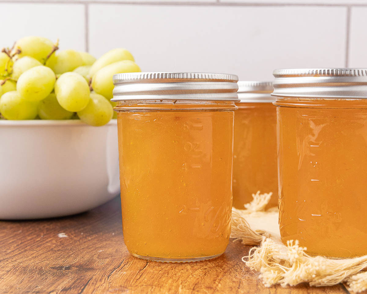 Jars of grape jelly sitting on a countertop.