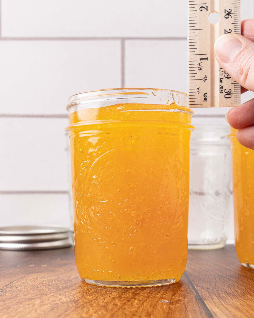 Homemade grape jelly ladled into a jar with 1/4" headspace.