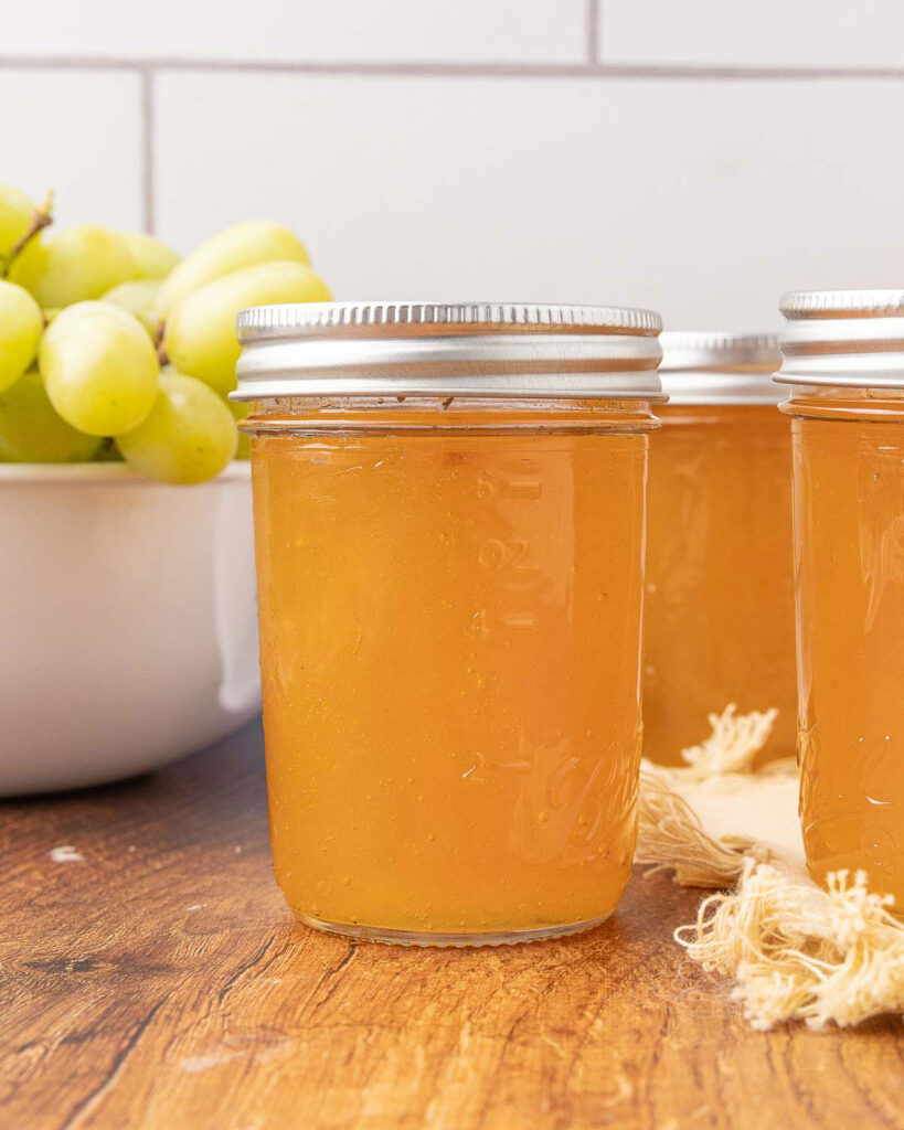 Jars of homemade grape jelly cooling on a countertop.