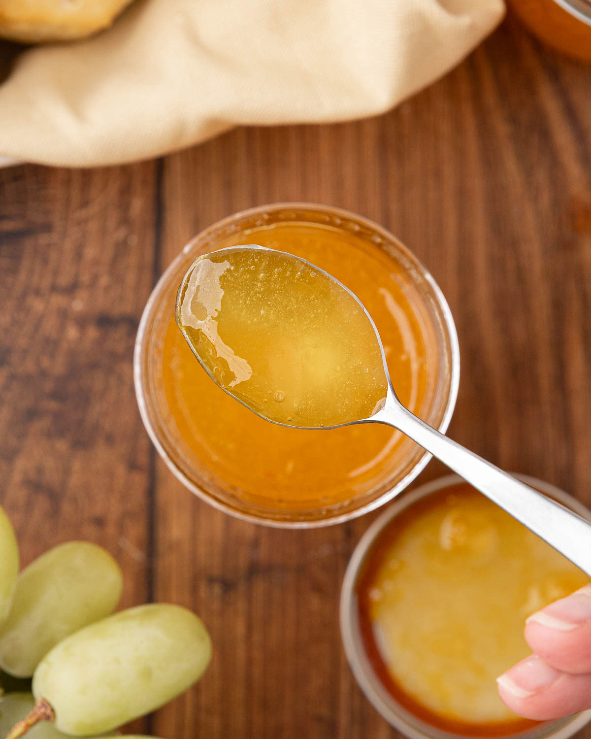 A jar of grape jelly with a spoon removing a serving to show texture.