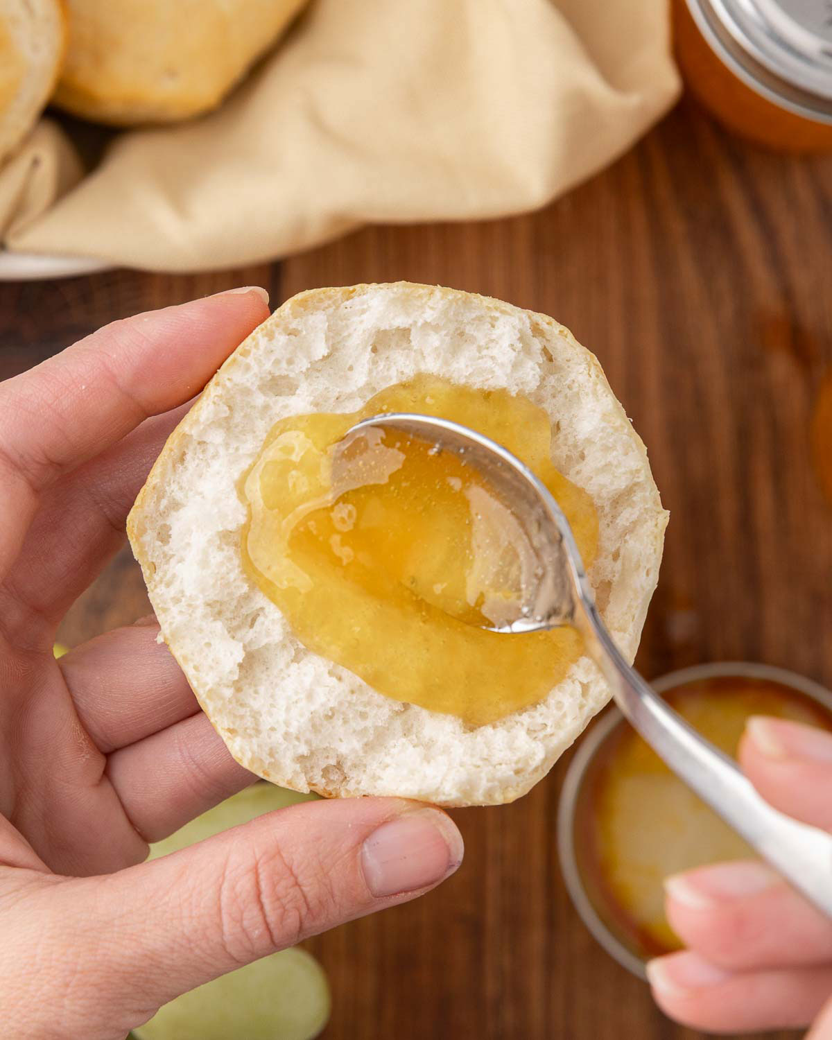 A spoon spreading homemade grape jelly on a piece of bread.