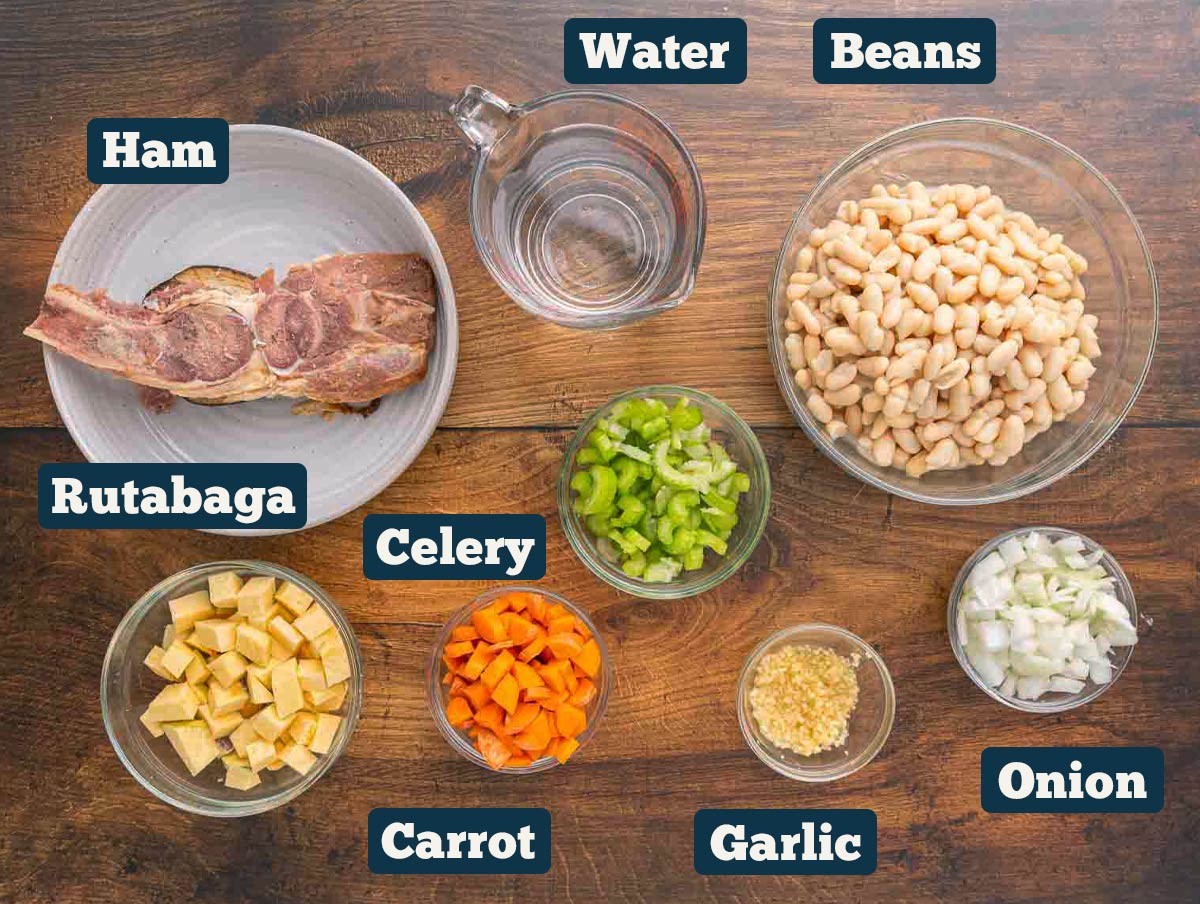 Ham and bean soup ingredients: ham bone, water, beans, rutabaga, carrot, celery, onion, and garlic.