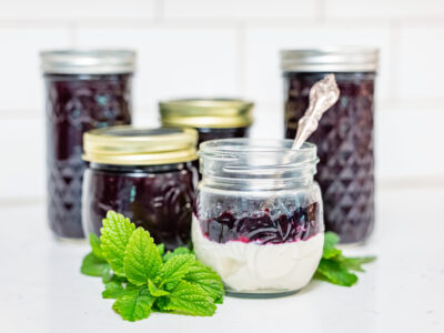 Jars of blueberry jam with a jar of yogurt topped with blueberry jam.