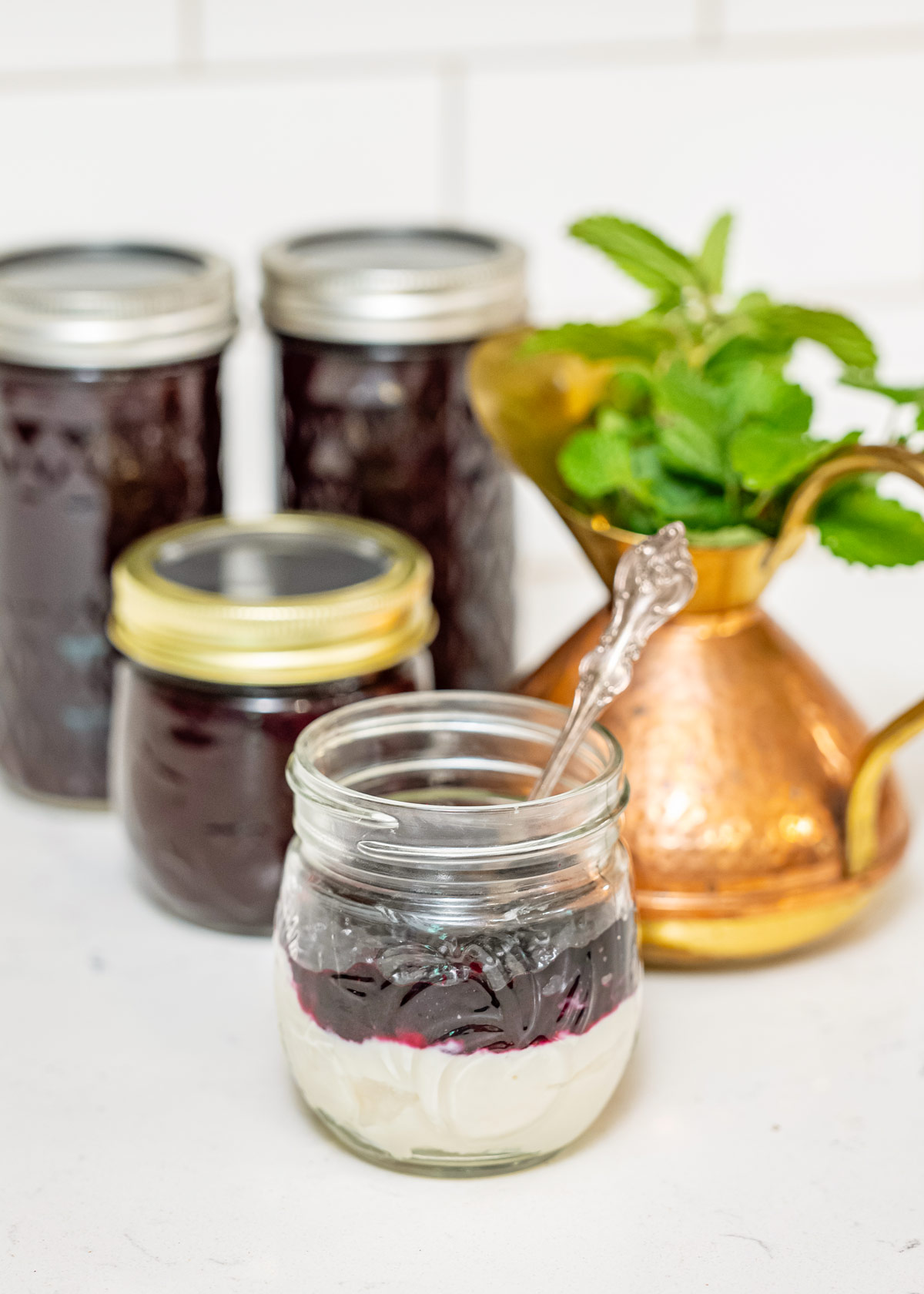 Jars of blueberry jam with a jar of yogurt topped with blueberry jam.