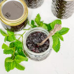 Jars of blueberry jam with a jar of yogurt topped with blueberry jam.