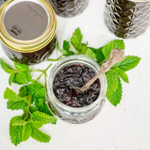 Jars of blueberry jam with a jar of yogurt topped with blueberry jam.