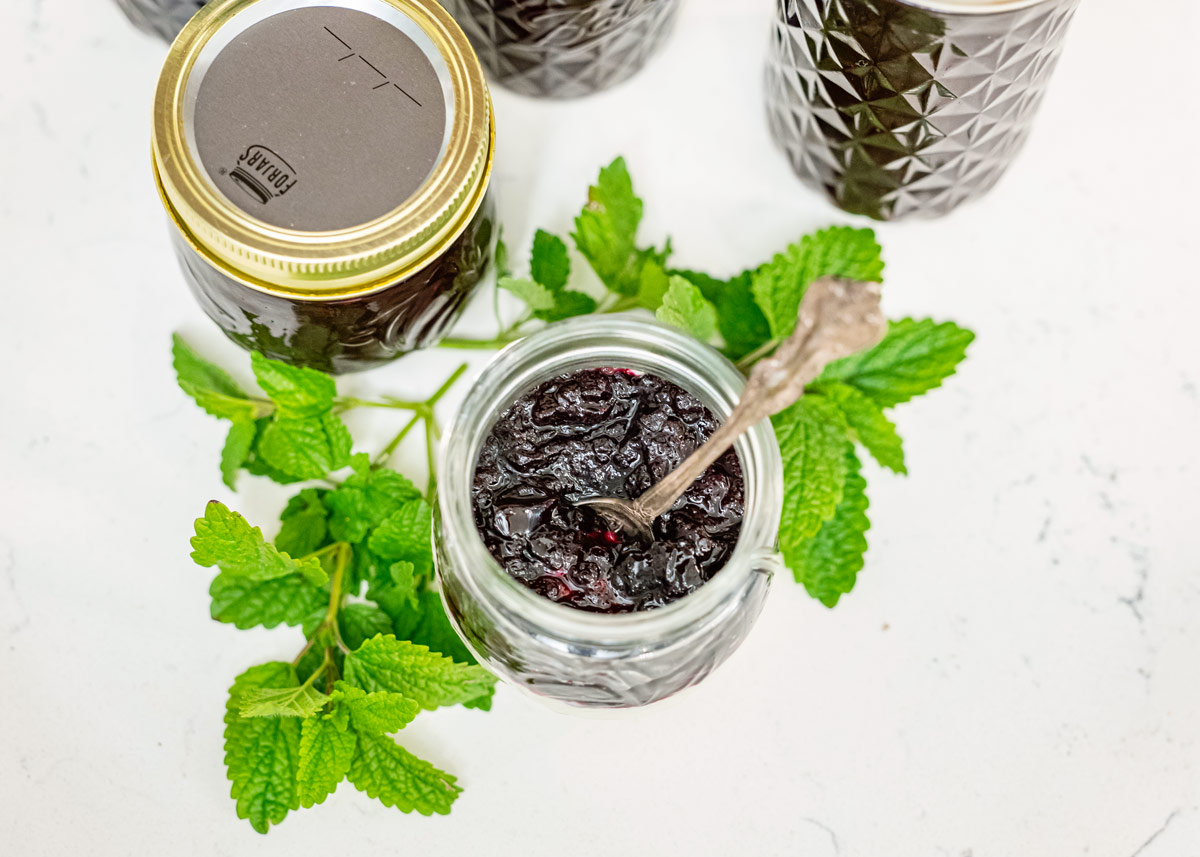 Jars of blueberry jam with a jar of yogurt topped with blueberry jam.