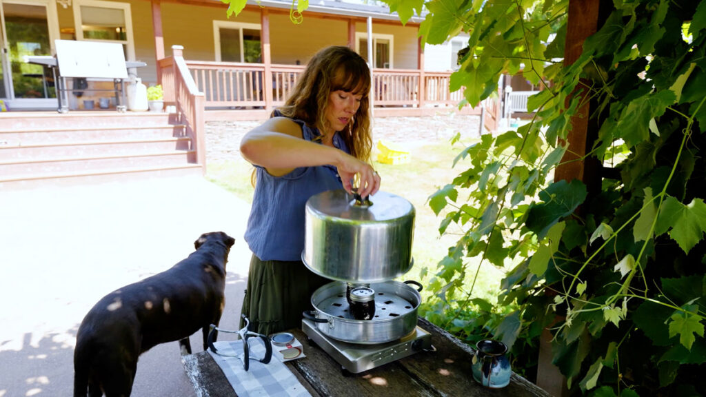 A woman removing the lid of a steam canner.