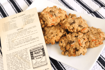 Plate of healthy carrot cookies on table with old newspaper bulletin