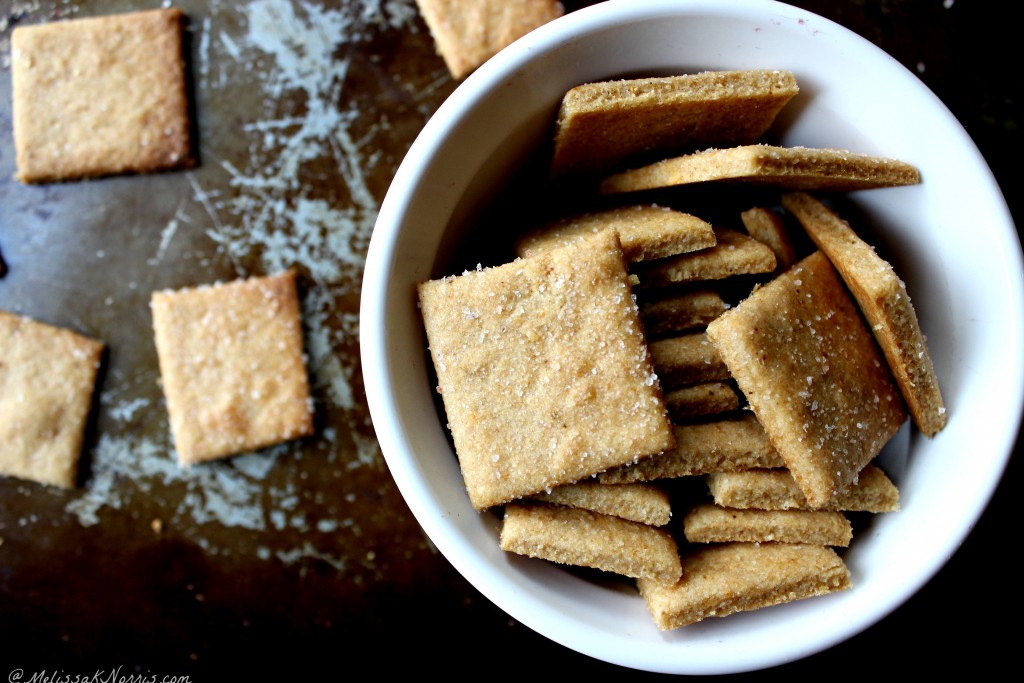 White bowl filled with homemade crackers and crackers on a baking sheet in the background.