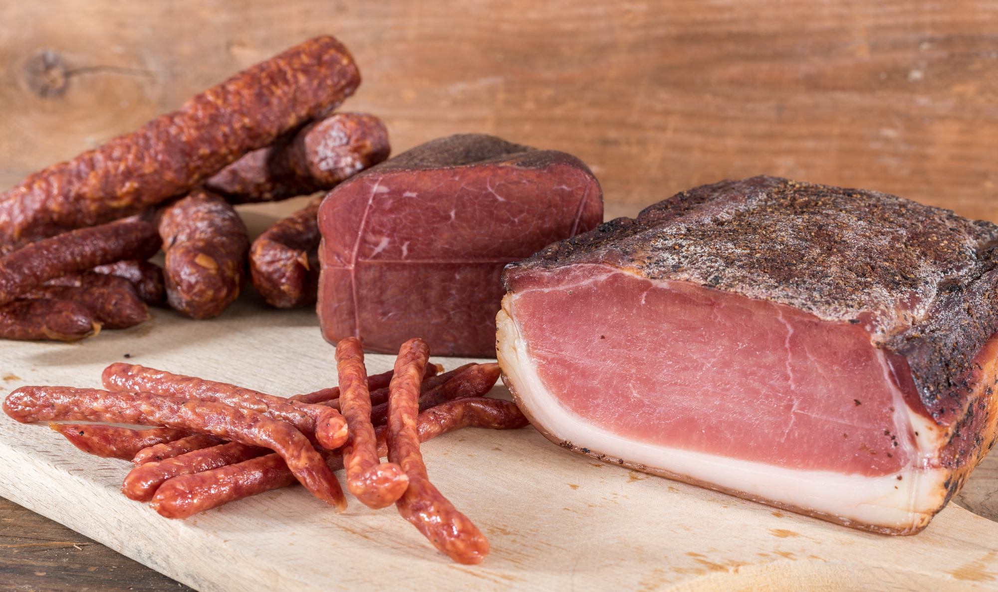 smoked sausages and meat on wooden table