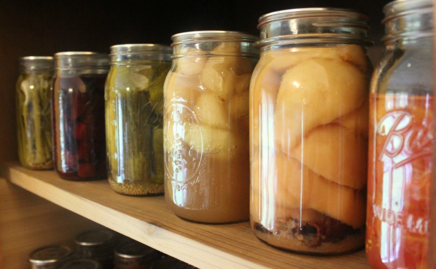 Jars of home canned food lining a pantry shelf.