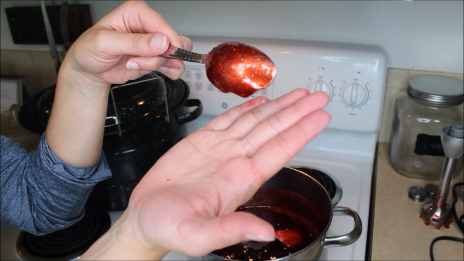 Woman holding up a spoon covered in jelly that's thick and not dripping off.