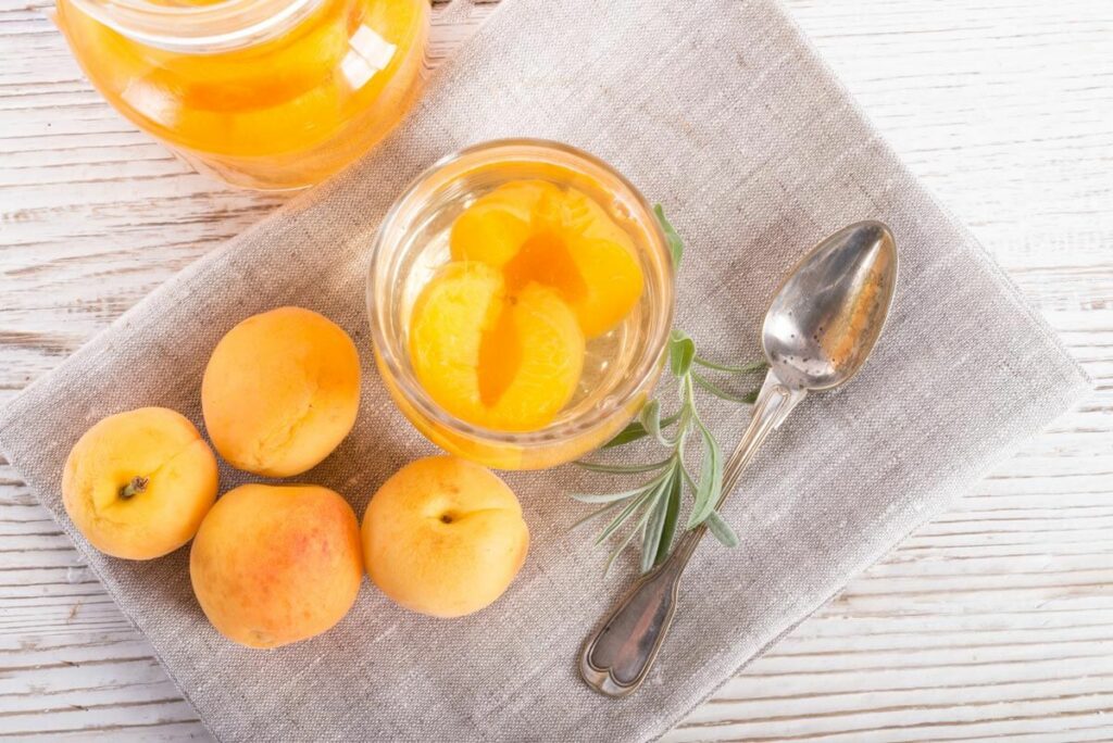 Canned apricots in a jar on a linen napkin.