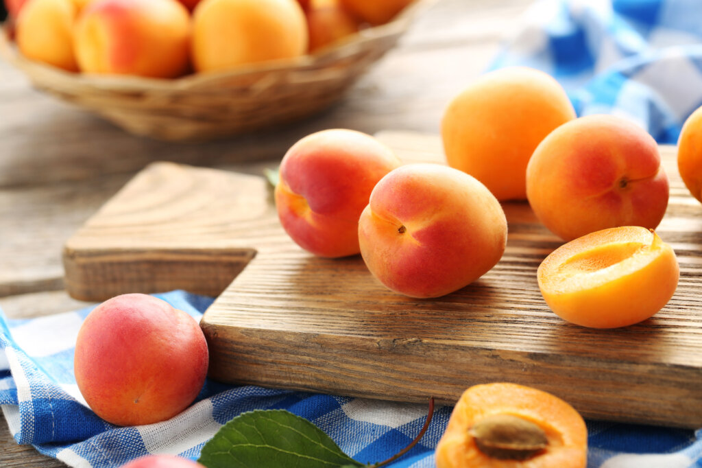 Apricots on a cutting board on a table.