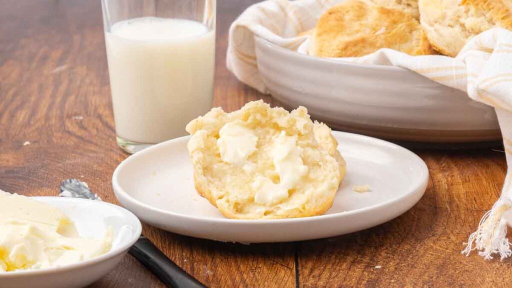 A buttered biscuit served on a white plate.