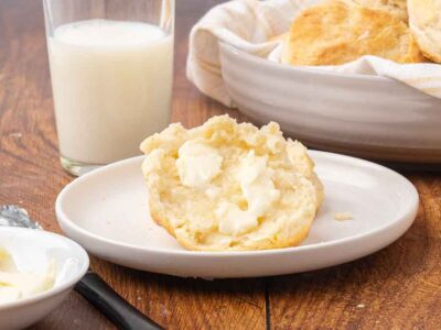 A buttered biscuit served on a white plate.