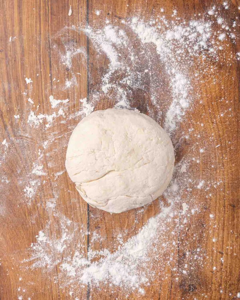 Biscuit dough shaped into a disc on a floured surface.
