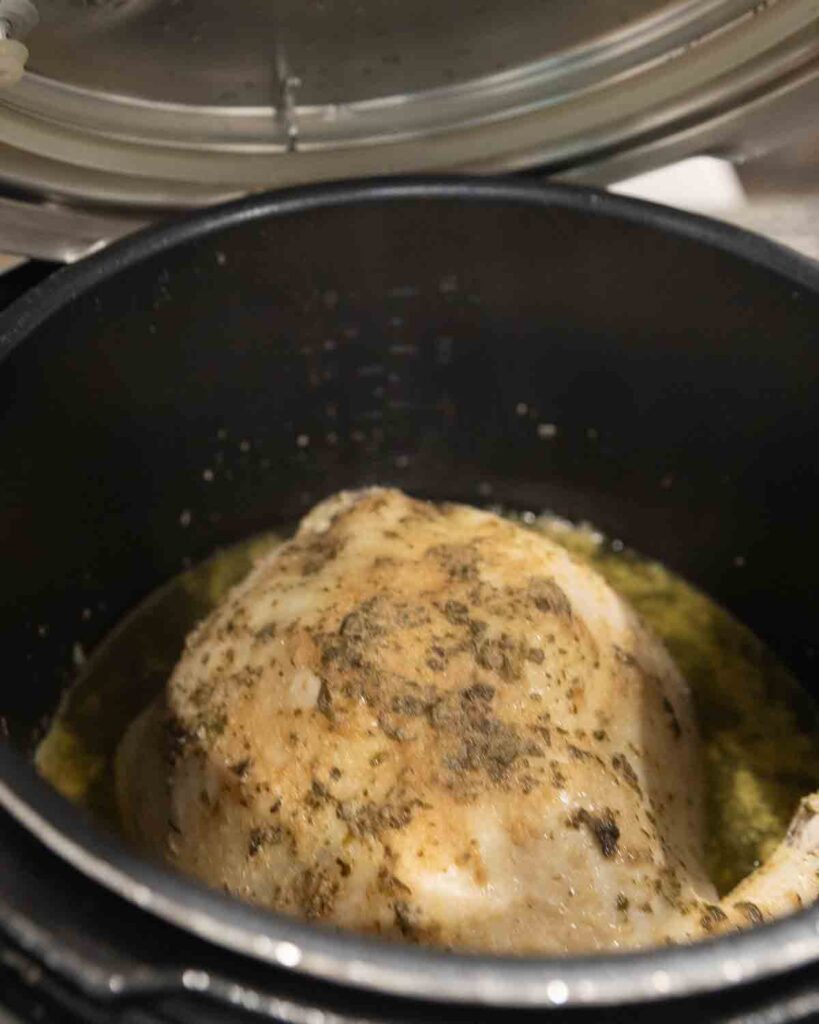 A cooked whole chicken sitting inside an Instant Pot.