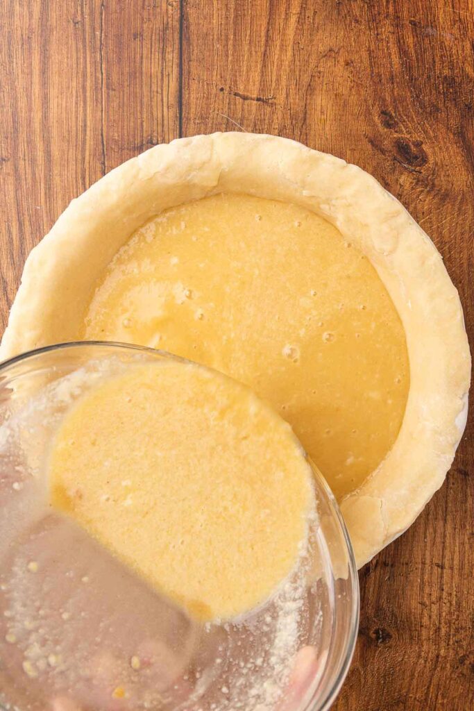 Pouring vinegar pie filling into a baked pie crust.