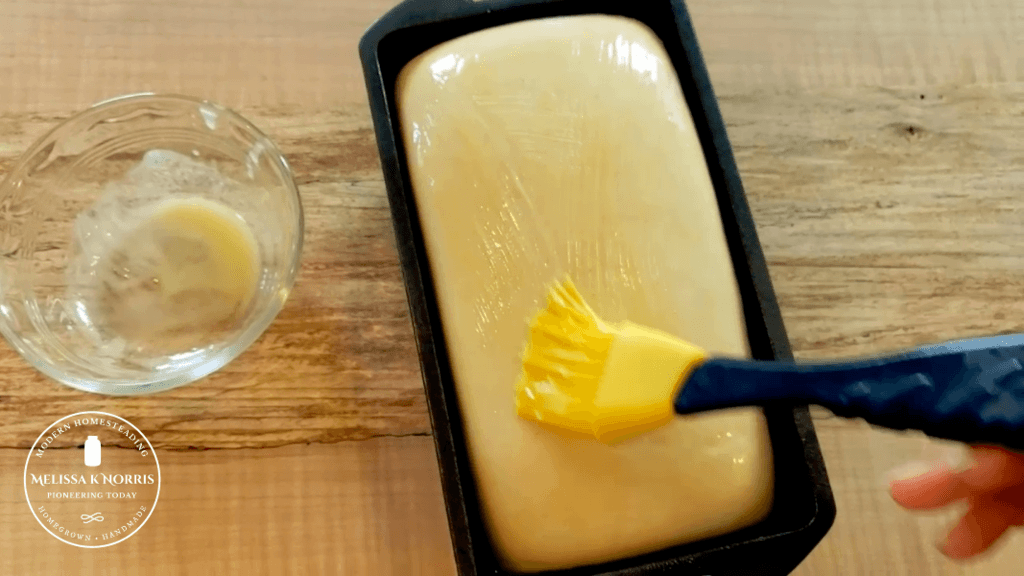 brushing melted butter on top of sourdough sandwich bread