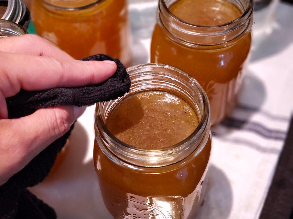Wiping the rim of a mason jar with a damp towel.