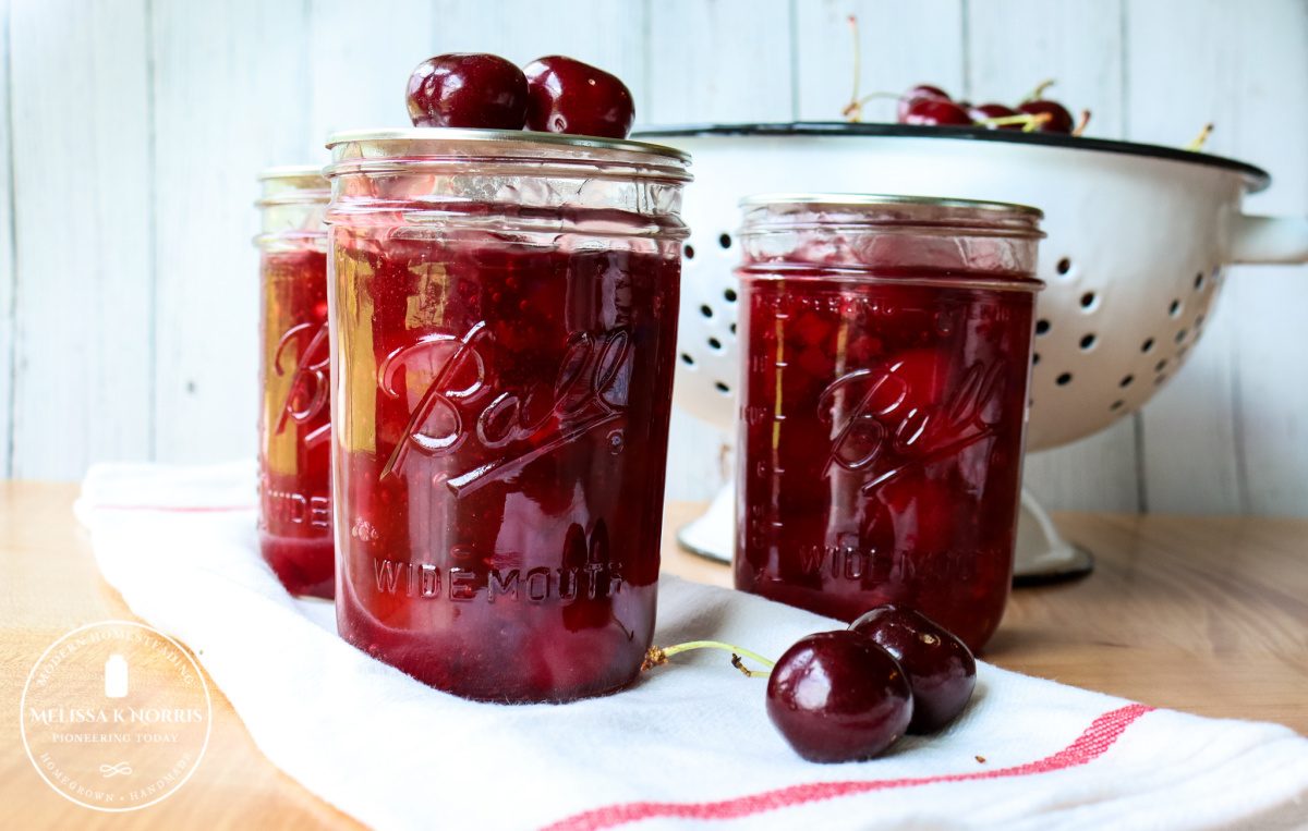 homemade cherry pie filling in mason jars on white towel