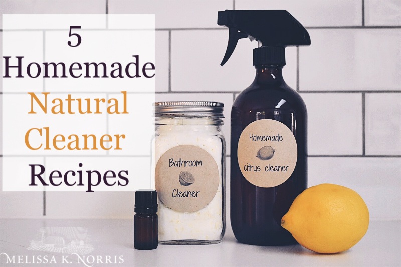 Image of a spray bottle, lemon, essential oils sitting on a counter for homemade natural cleaners.