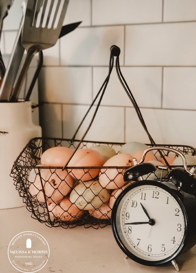 A basket of farm fresh eggs with a clock sitting in front of it.