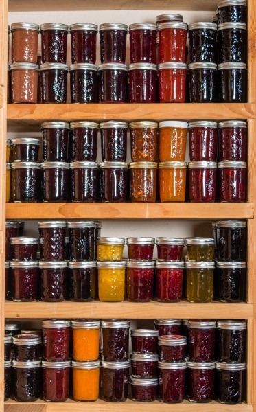 Picture of food pantry shelves lined with Mason jar filled with colorful fruits, vegetables, and jams. Text overlay says, "Home Food Preservation - Create Your Preserving Plan for a Years Worth of Food".