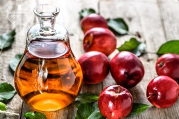 homemade fruit vinegar in bottle and apples on table