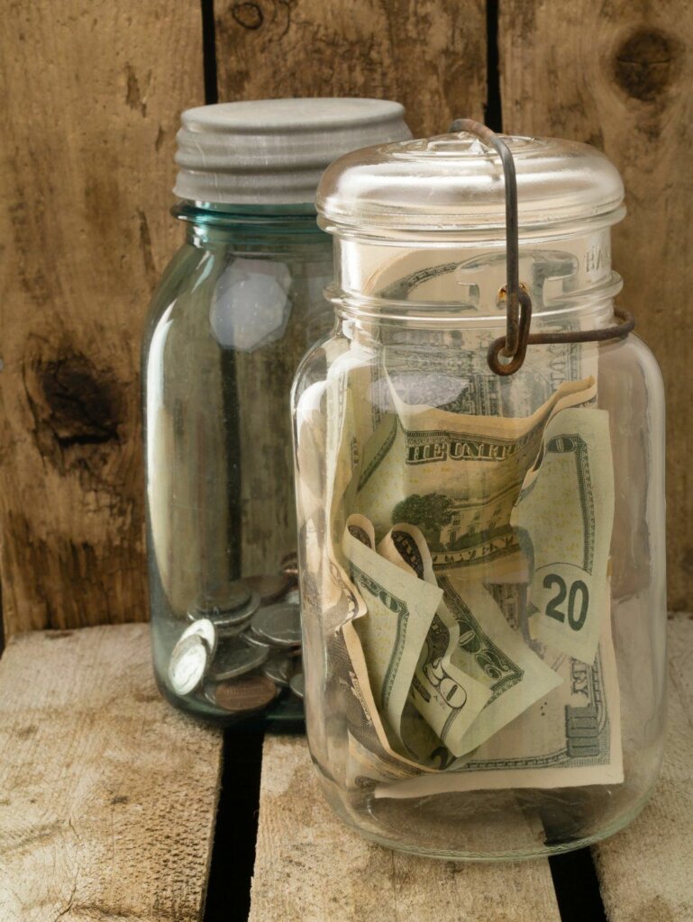 Two old Mason jars with paper money and coins. 