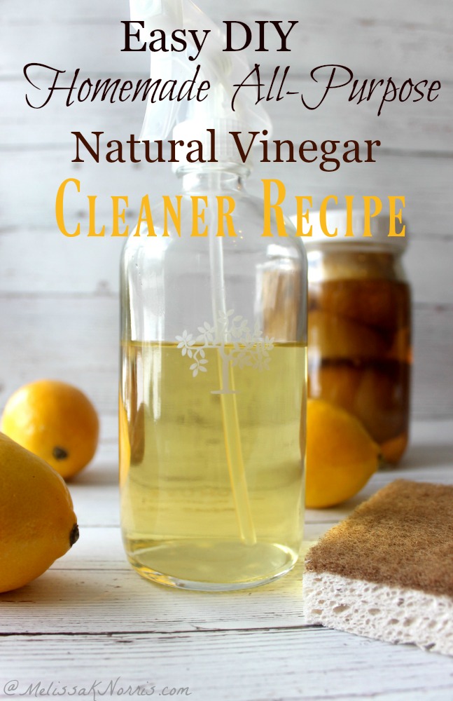 Picture of a glass spray bottle filled with vinegar cleaner in the forefront, and a Mason jar filled with lemons and vinegar in the background. Fresh lemons are scattered in between. Text overlay says "Natural Vinegar Cleaner Recipe".