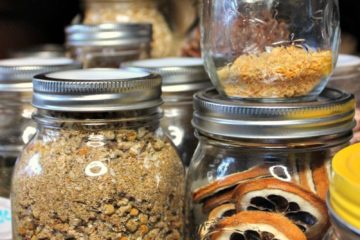 Various sizes of mason jars with food in them. Text overlay says, "7 Tips to Organize & Build Your Homestead Kitchen & Food Storage"