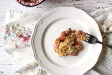 A white plate with a helping of strawberry rhubarb dump cake and a fork. Text overlay says, "Strawberry Rhubarb Dump Cake Real Food Style: Homemade Cake Mix & No Jello".