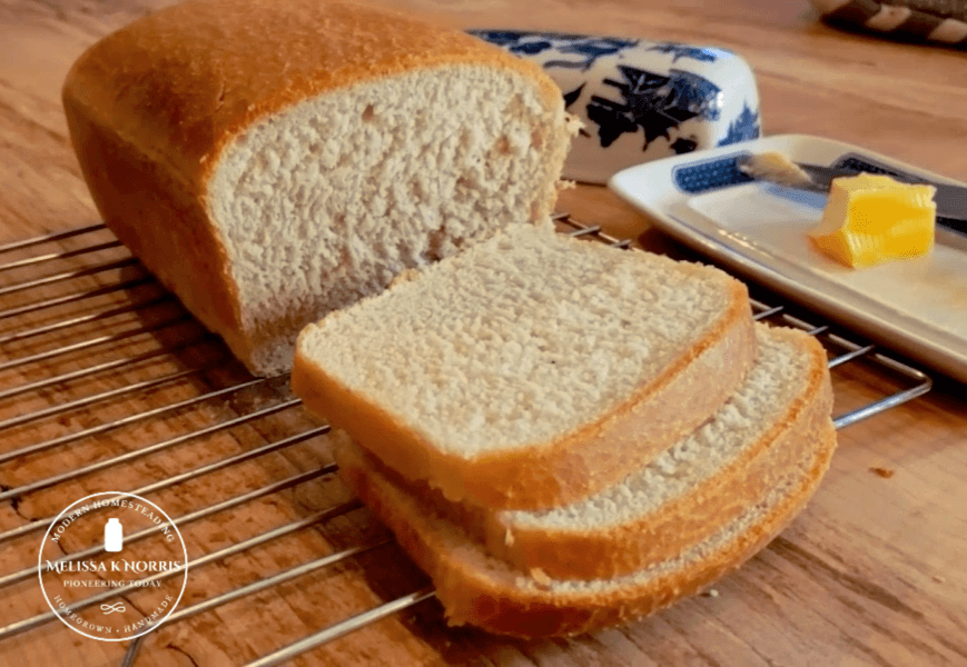 Sliced loaf of sourdough bread with butter in the background.