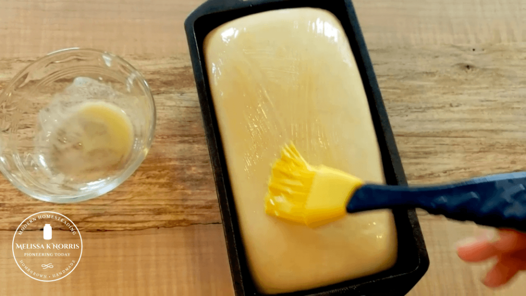 A loaf of bread being buttered.