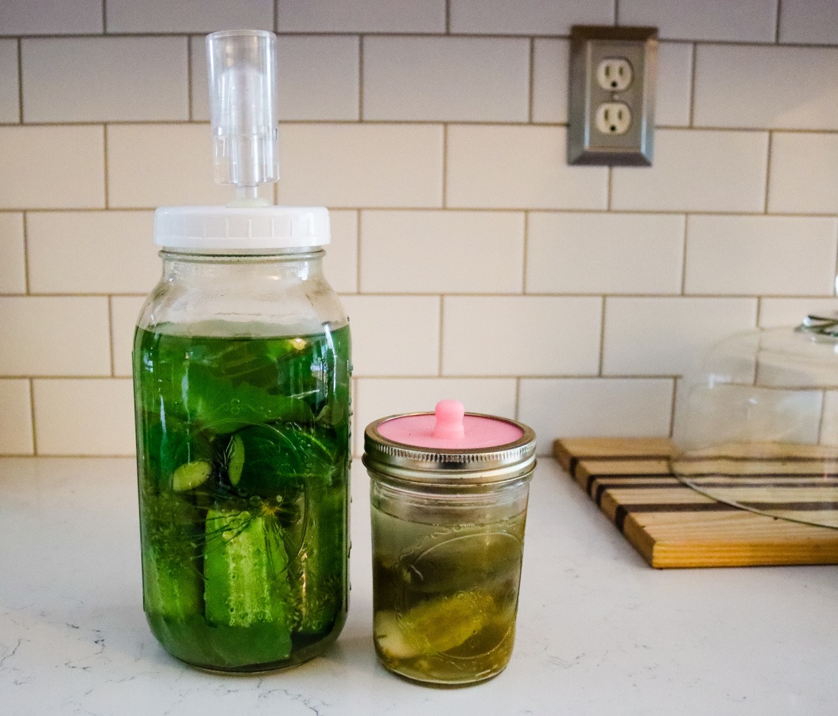 Mason jar filled with pickles sitting on a towel on a table. Text overlay says, "Old Fashioned Salt Water Brine Fermented Pickles."