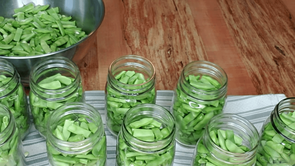 Pouring boiling water onto fresh green beans before pressure canning