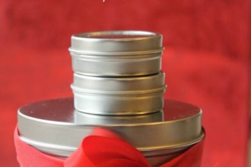 Pinterest pin with an image of various sized round tins stacked on top of each other, and tied with a bow. Text overlay reads "Homemade Peppermint Salve (for dry winter skin)".
