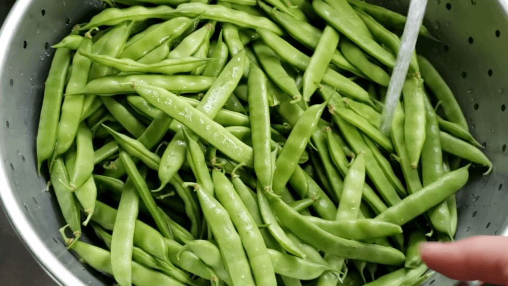 fresh green beans being snapped in bowl on counter for pressure canning