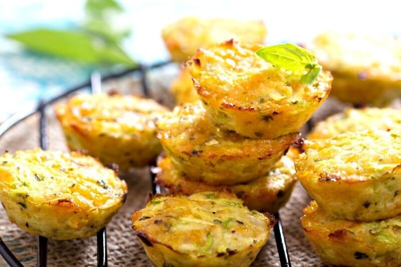 Zucchini breakfast muffins stacked on a cooking rack.