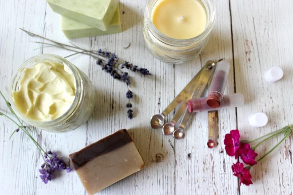 Homemade personal care items like lip balm, body butter and homemade soap sitting on a counter.