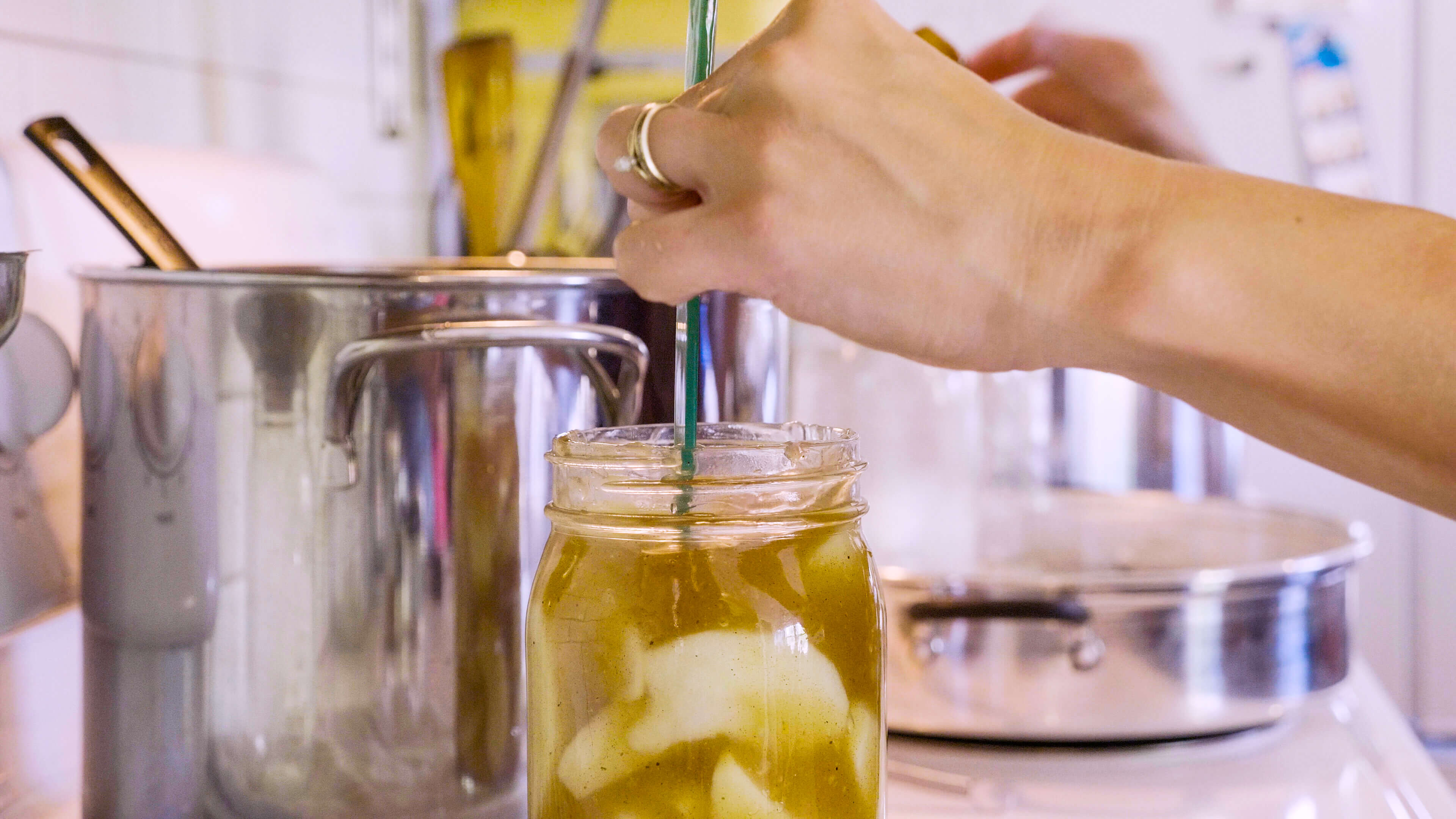 A woman's hand measuring the head space in a mason jar filled with apple pie filling.