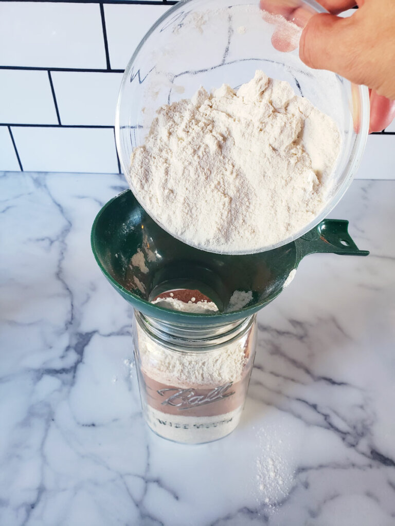 Flour being poured through a funnel into a mason jar.