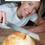 Pinterest pin for artisan bread with an image of a woman slicing into a fresh baked loaf.